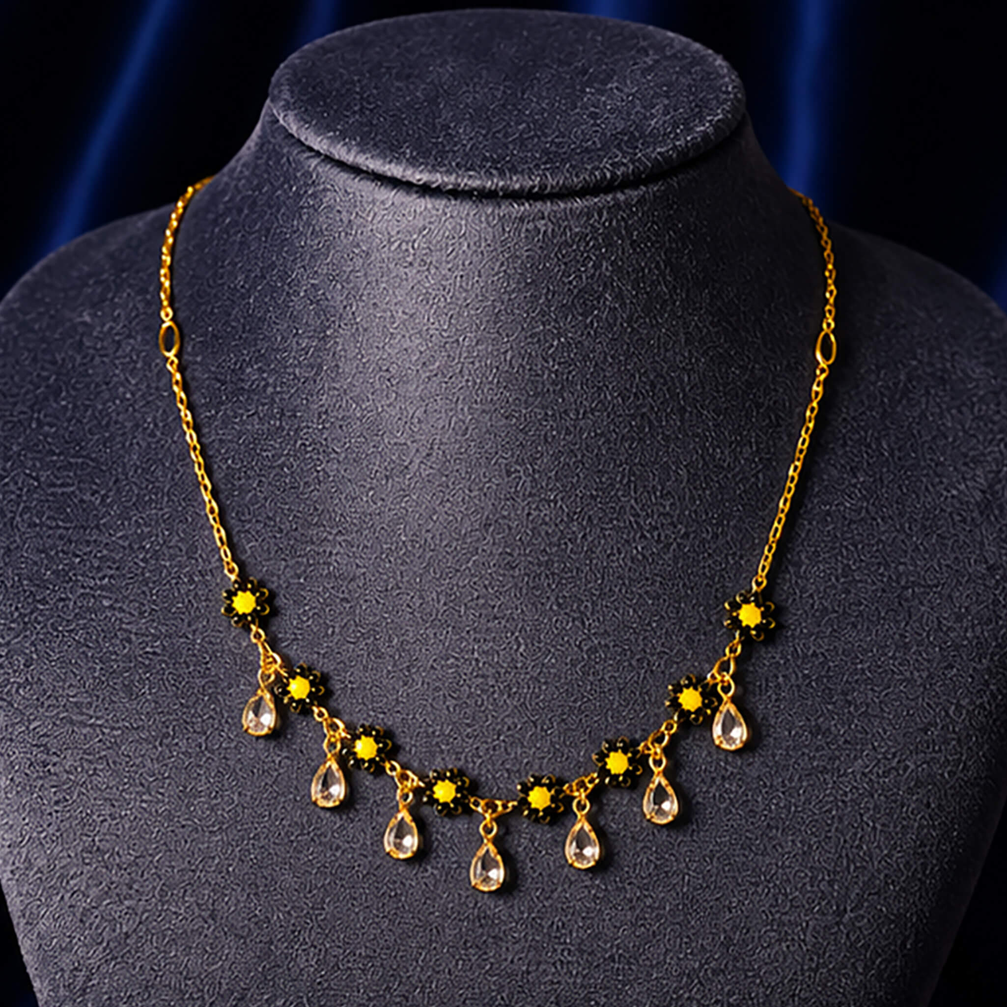 Gold-tone floral necklace featuring sunflower-inspired yellow stones and crystal drop charms displayed on a jewelry bust.