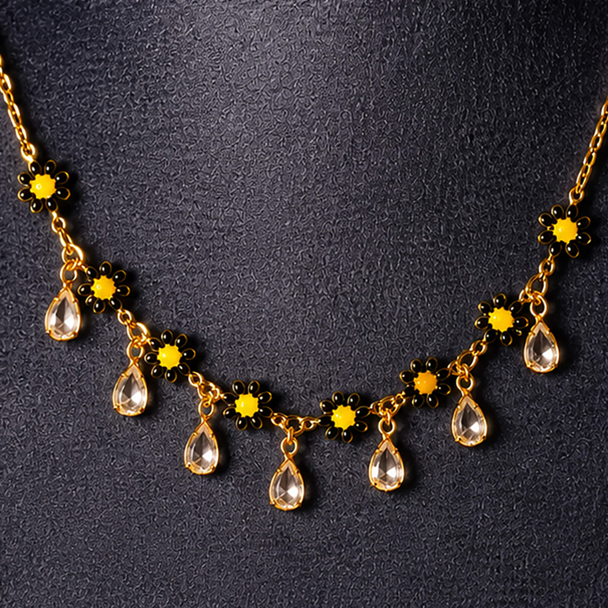 Gold-tone floral necklace featuring sunflower-inspired yellow stones and crystal drop charms displayed on a jewelry bust.
