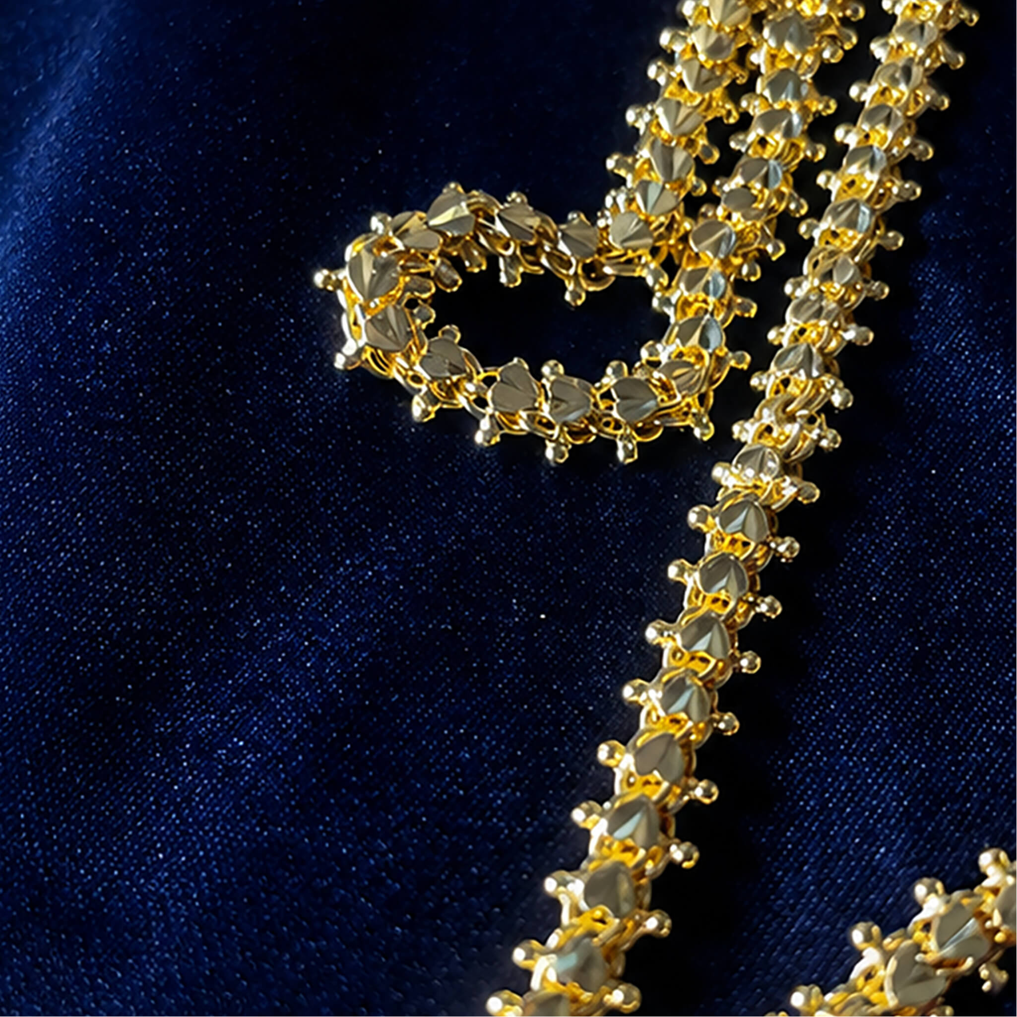 Elegant gold-tone heritage long chain with intricate bead detailing displayed on a luxurious navy blue fabric background.