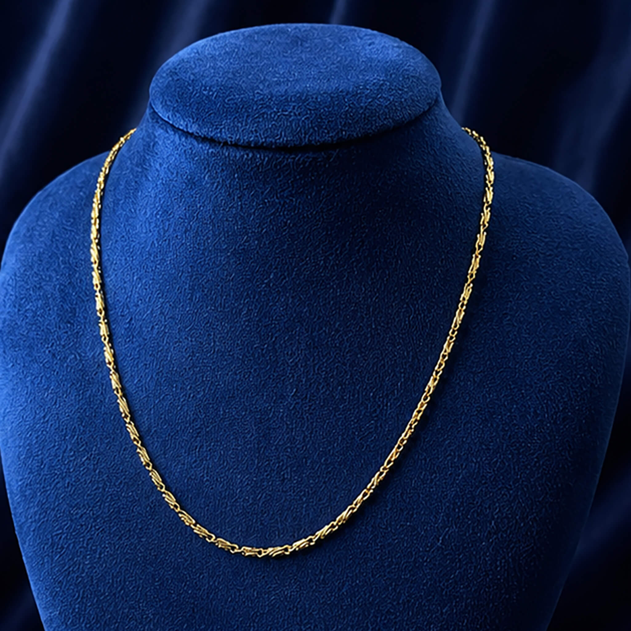 Aurelia Delicate Golden Twist Chain displayed on a royal blue velvet jewelry bust.
