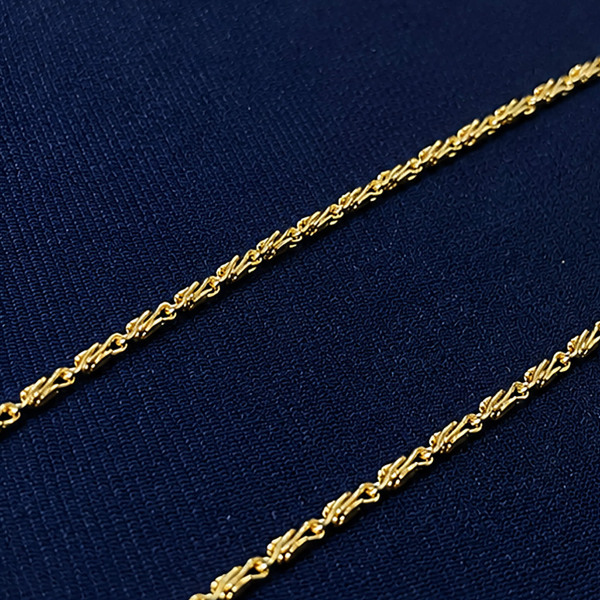 Aurelia Delicate Golden Twist Chain displayed on a royal blue velvet jewelry bust.