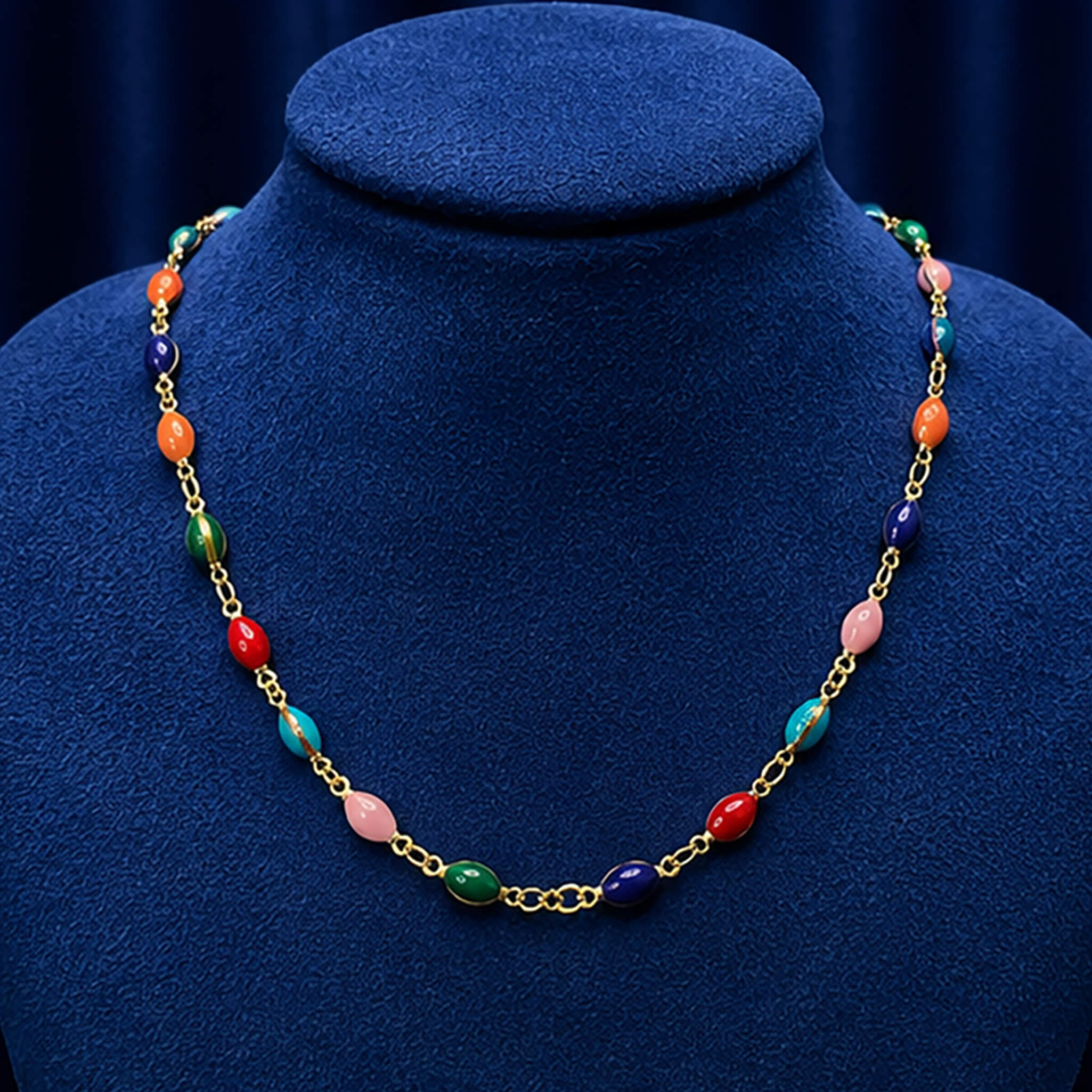 Gold-tone necklace featuring vibrant multicolored beads displayed on a royal blue velvet jewelry bust.