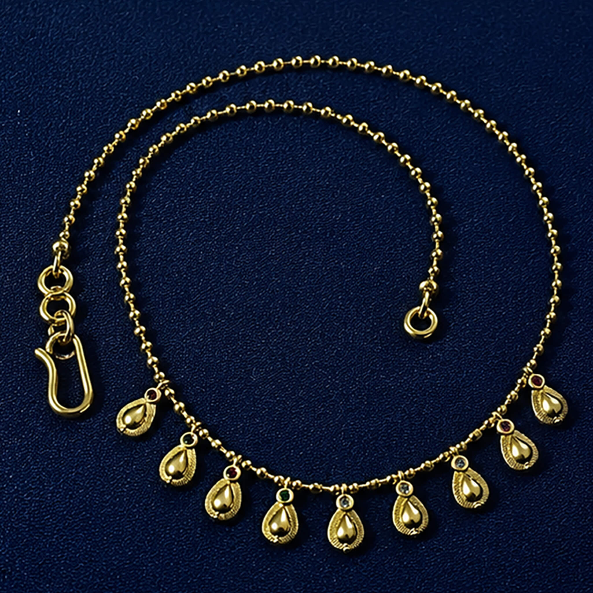 Gold-tone necklace with dangling teardrop charms displayed on a royal blue velvet jewelry bust.