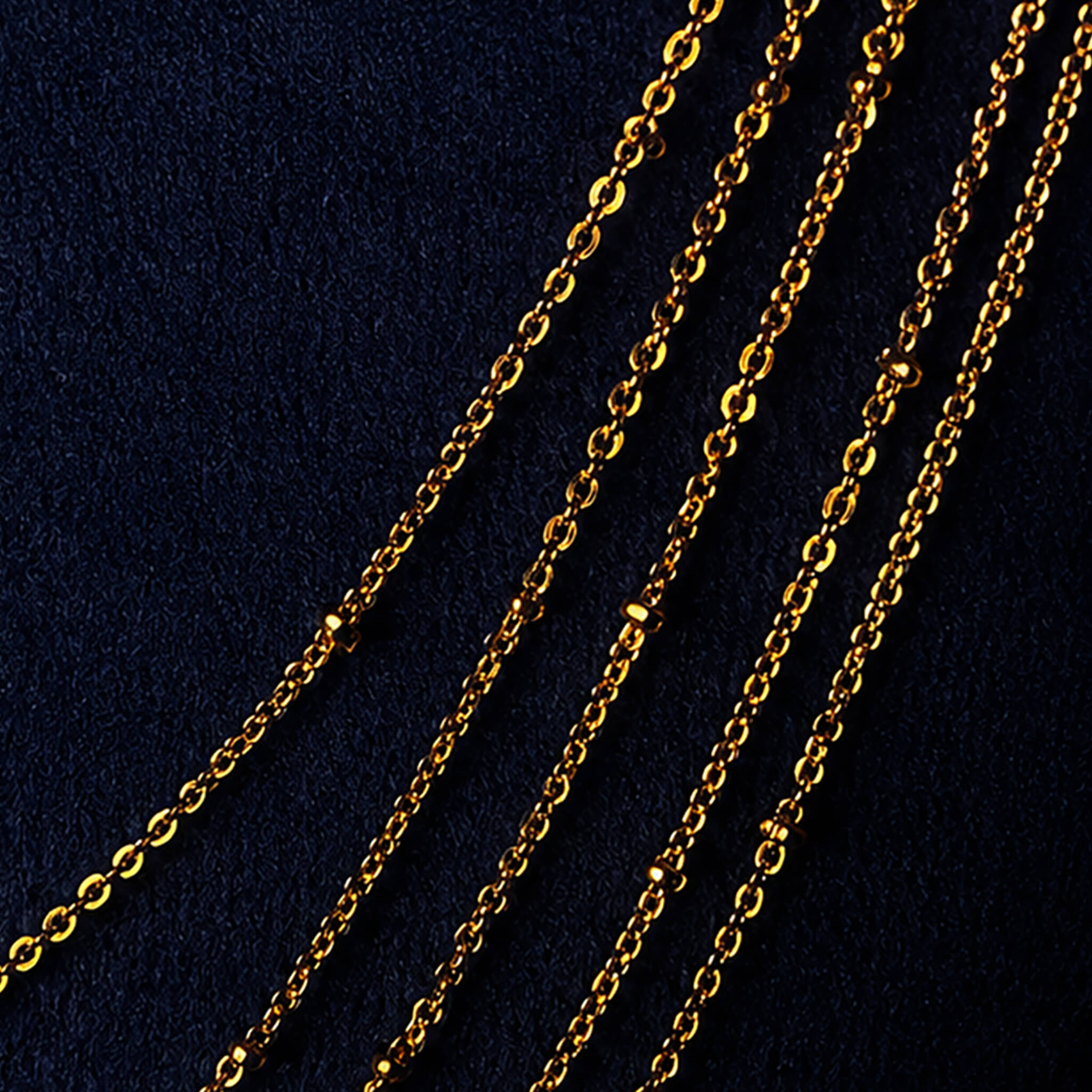 Elegant multi-layer gold-tone long chain displayed on a black jewelry bust against a dark blue background.