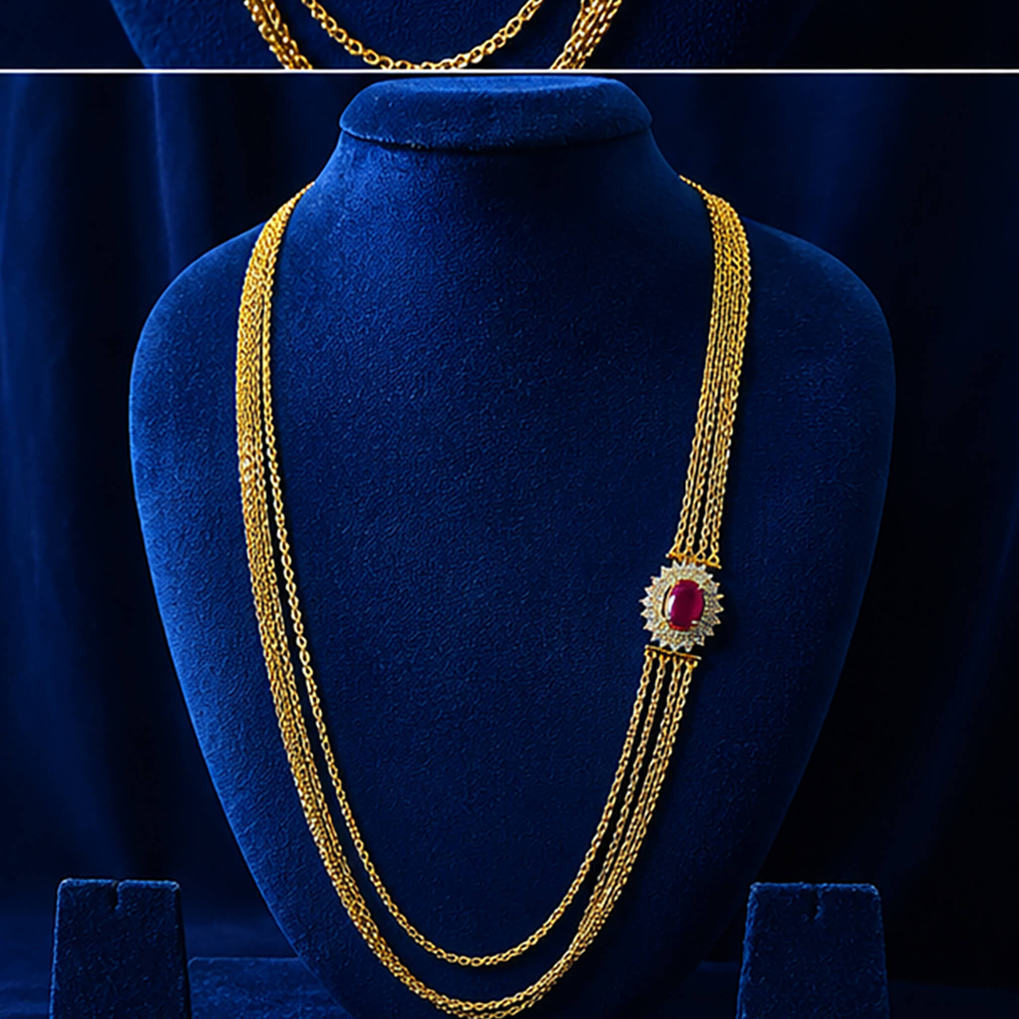 Multi-layered gold-tone Chandraharam with ruby-red floral centerpiece displayed on a royal blue velvet jewelry bust.