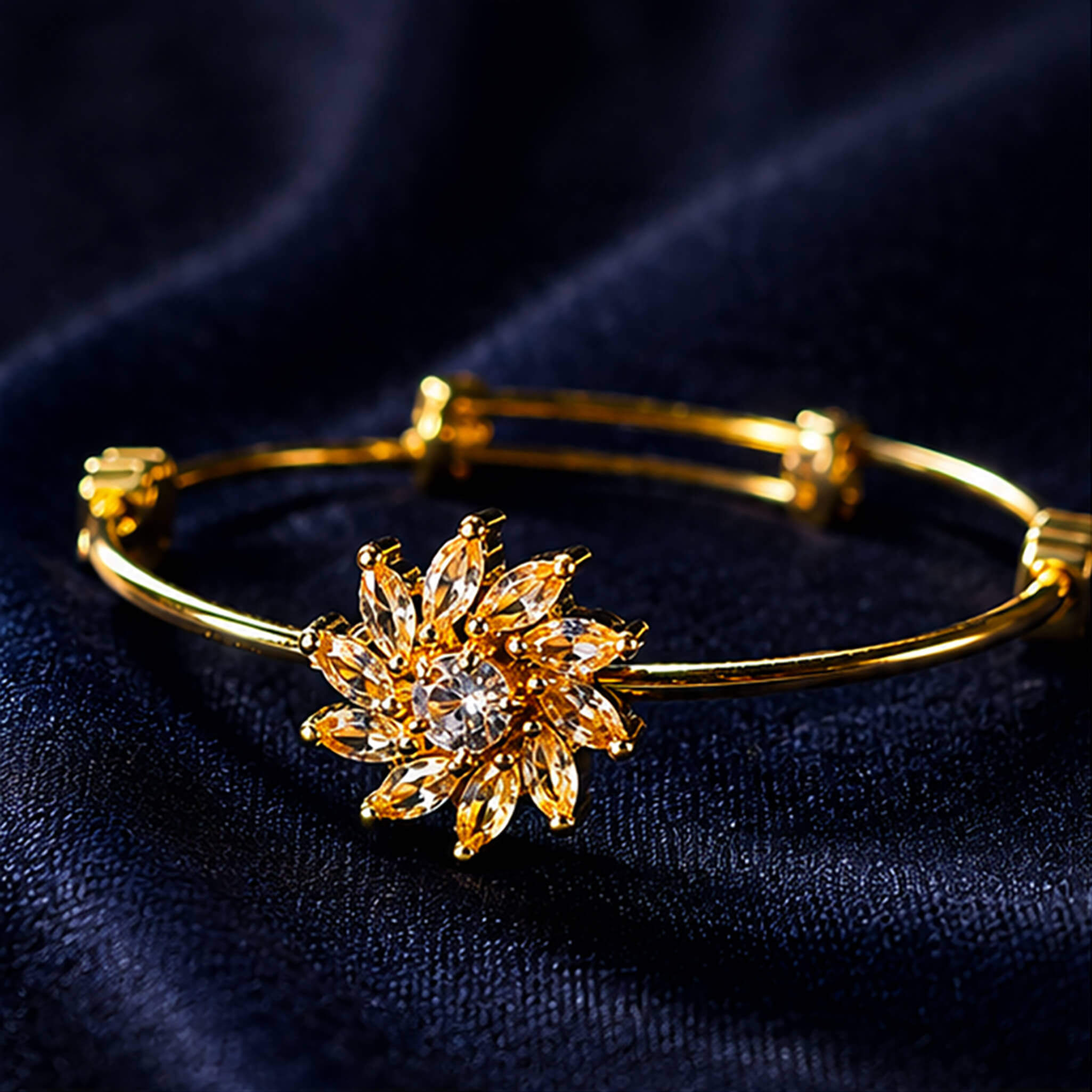 Gold-tone bracelet featuring a sparkling floral crystal centerpiece displayed on a luxurious navy blue velvet background.