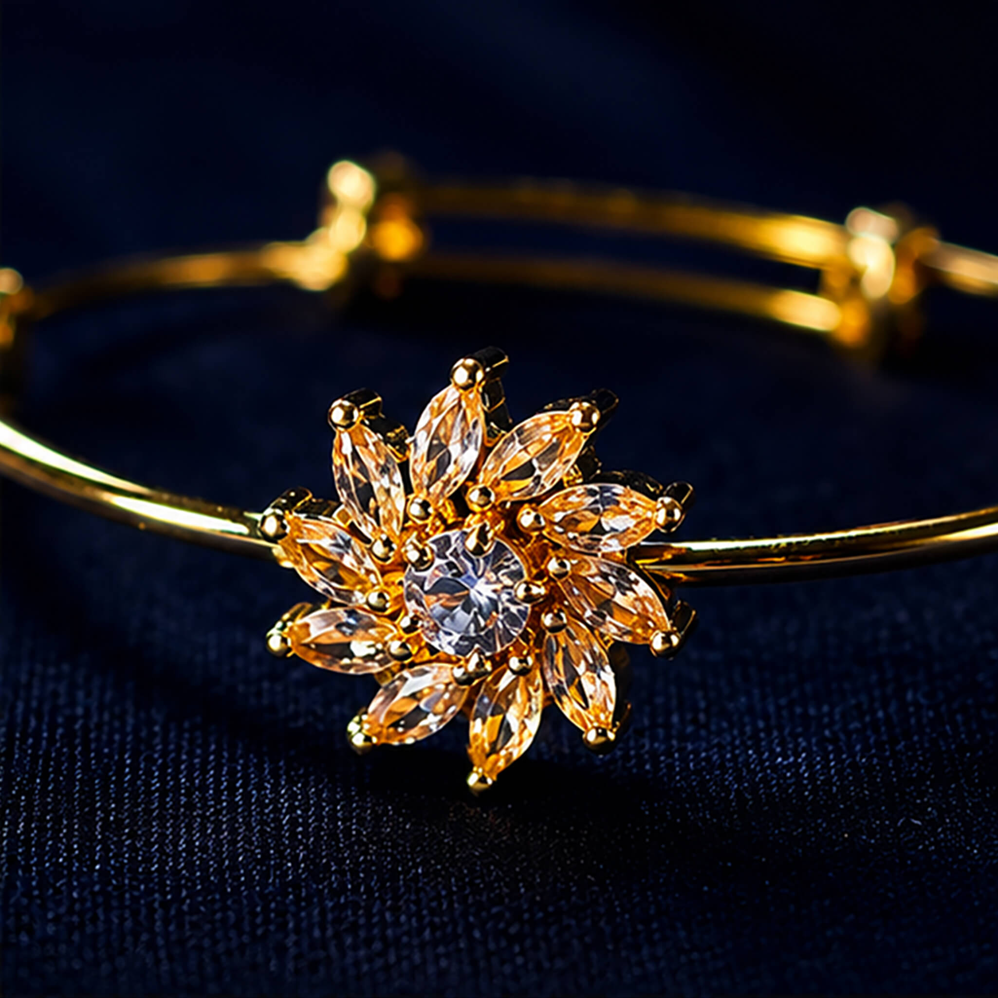 Gold-tone bracelet featuring a sparkling floral crystal centerpiece displayed on a luxurious navy blue velvet background.