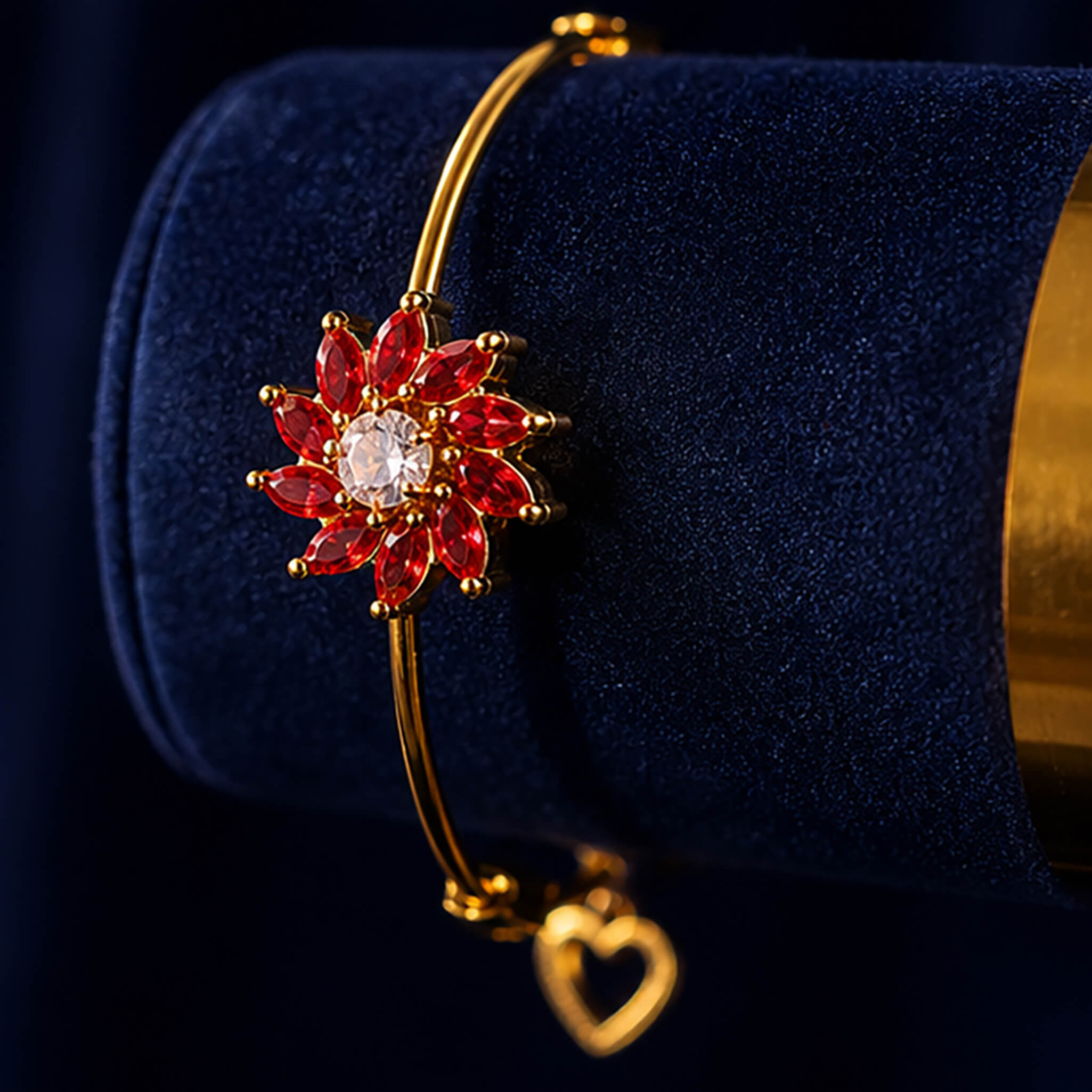 Gold-tone adjustable bracelet with ruby-red floral centerpiece and crystal stone on a luxurious dark blue background.