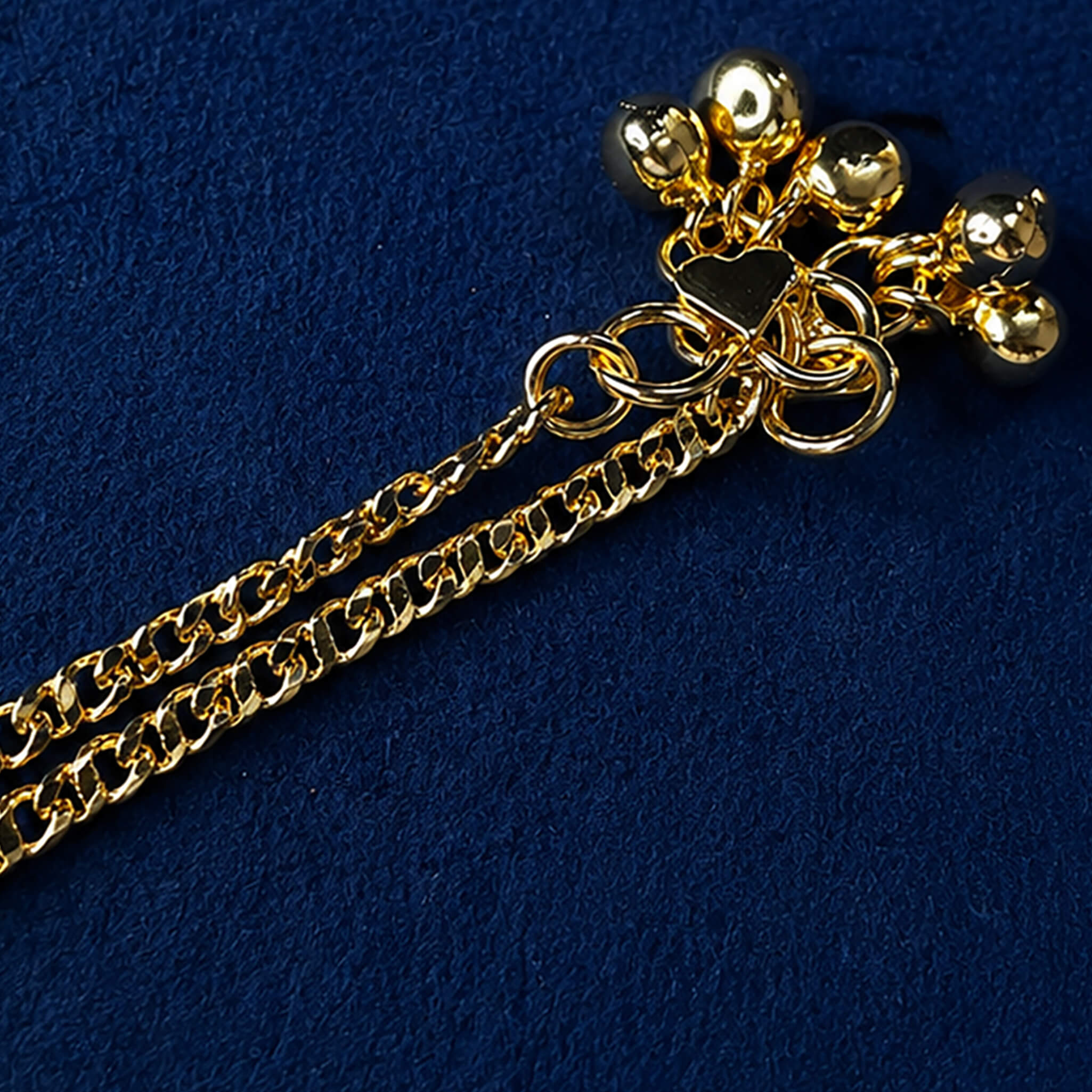 Double-layer gold-tone anklet with dangling bead charms displayed on a royal blue velvet background.