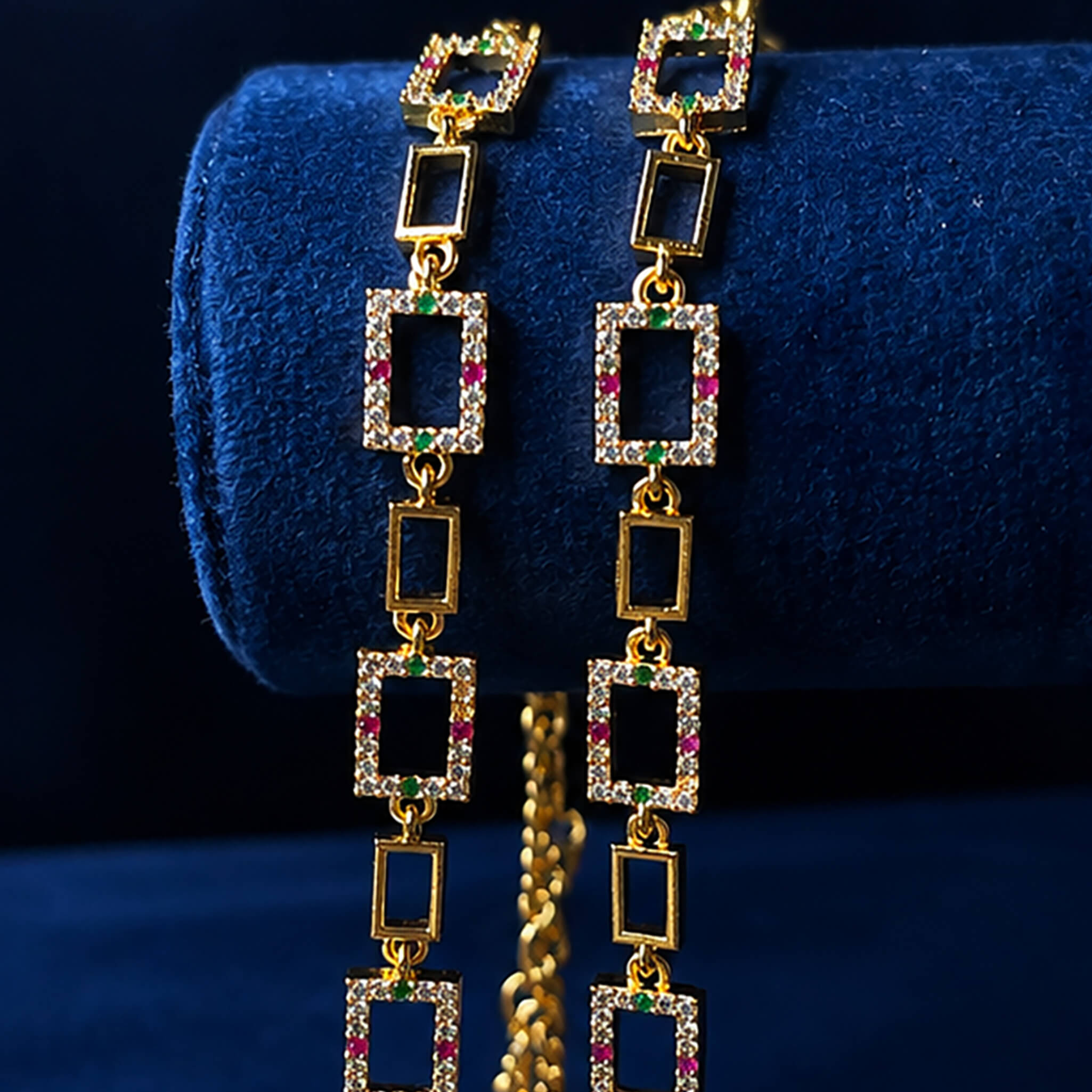 Double-layer gold-tone anklet with dangling bead charms displayed on a royal blue velvet background.