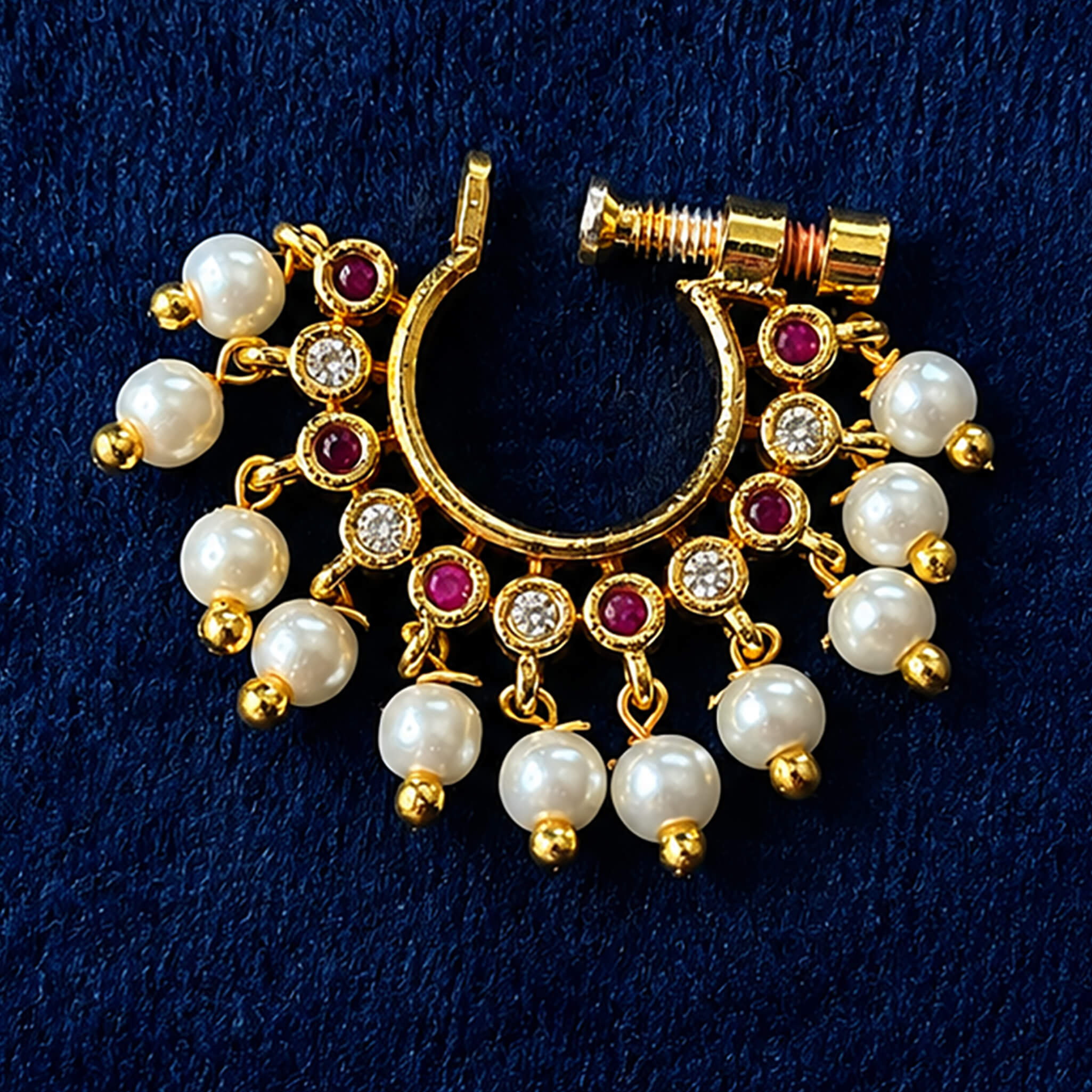 Traditional gold-tone nose ring with pearl drops, crystal accents, and ruby-colored stones displayed on a jewelry stand.