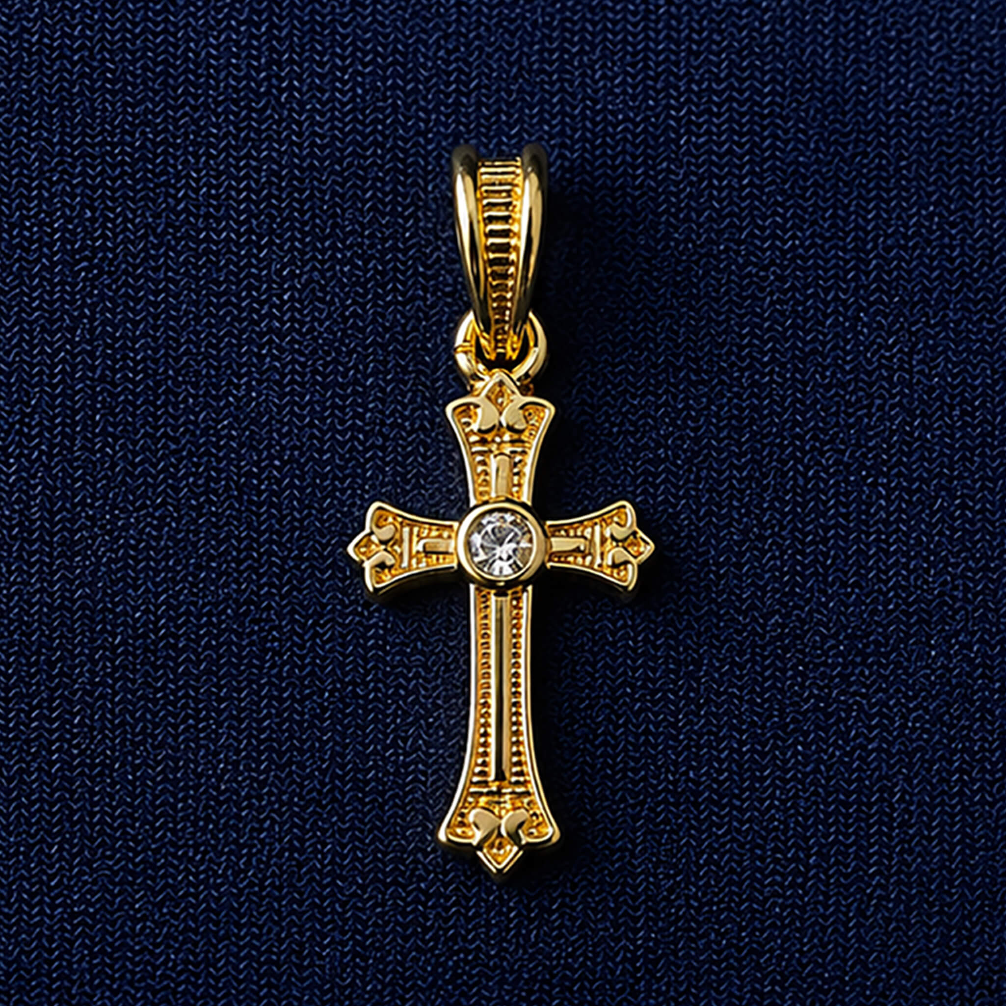 Gold-tone Christian cross pendant with decorative detailing and sparkling center stone on a royal blue velvet display.