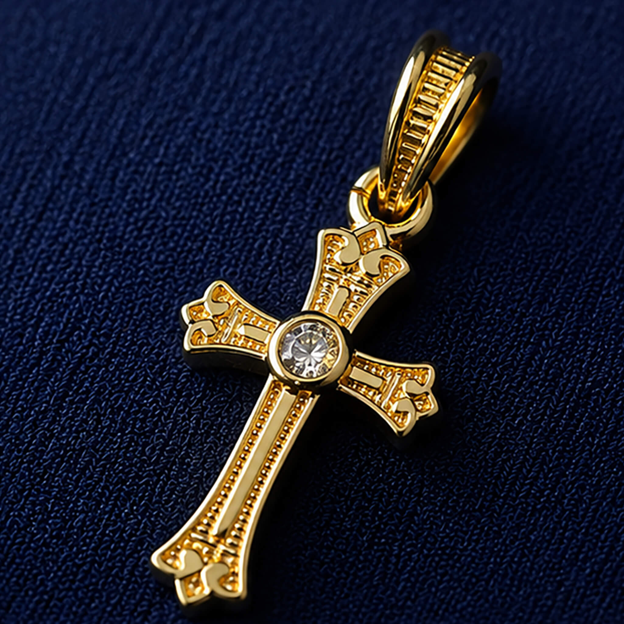Gold-tone Christian cross pendant with decorative detailing and sparkling center stone on a royal blue velvet display.