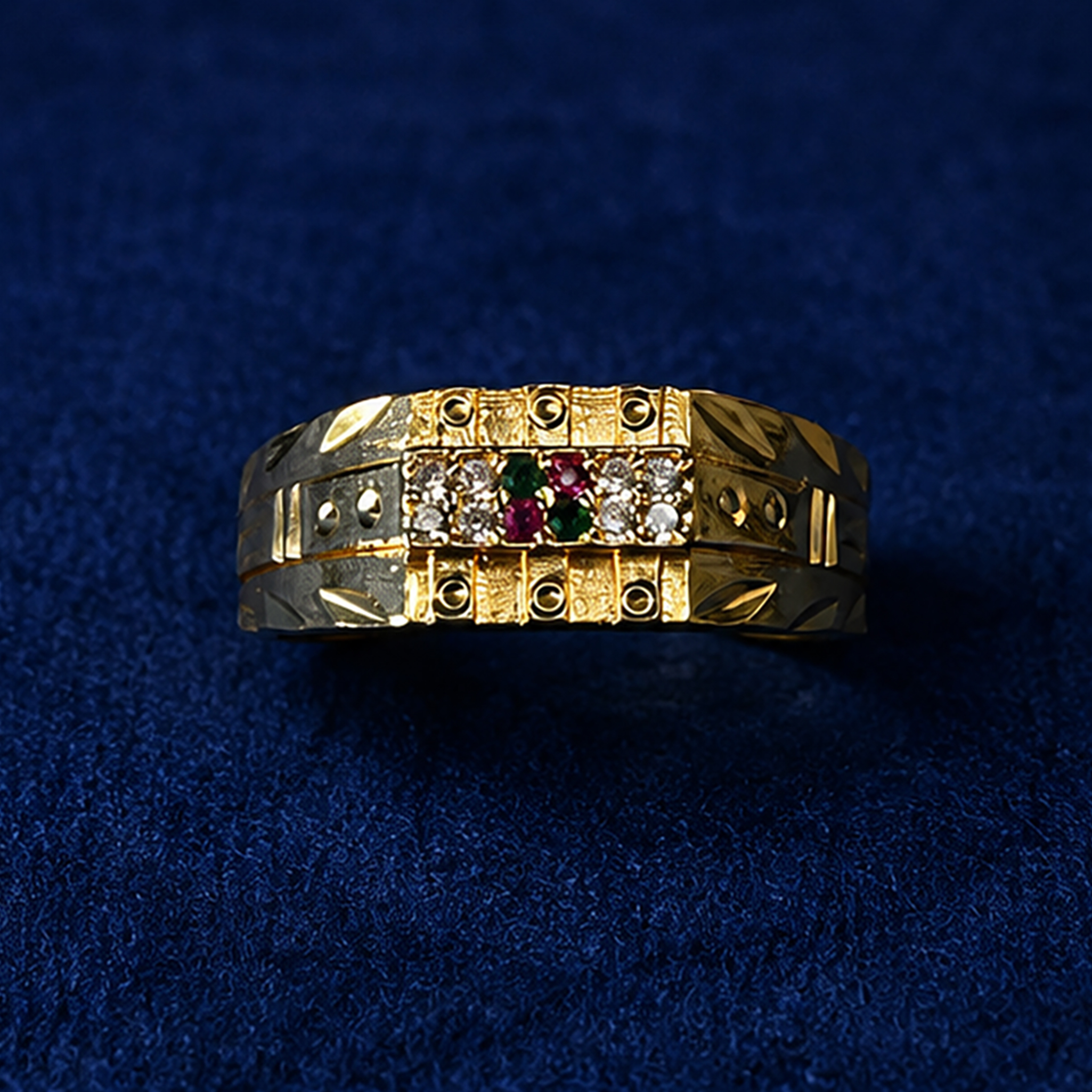 Dual-tone gold and silver ring featuring crystal stones with ruby and emerald accents on a royal blue velvet background.