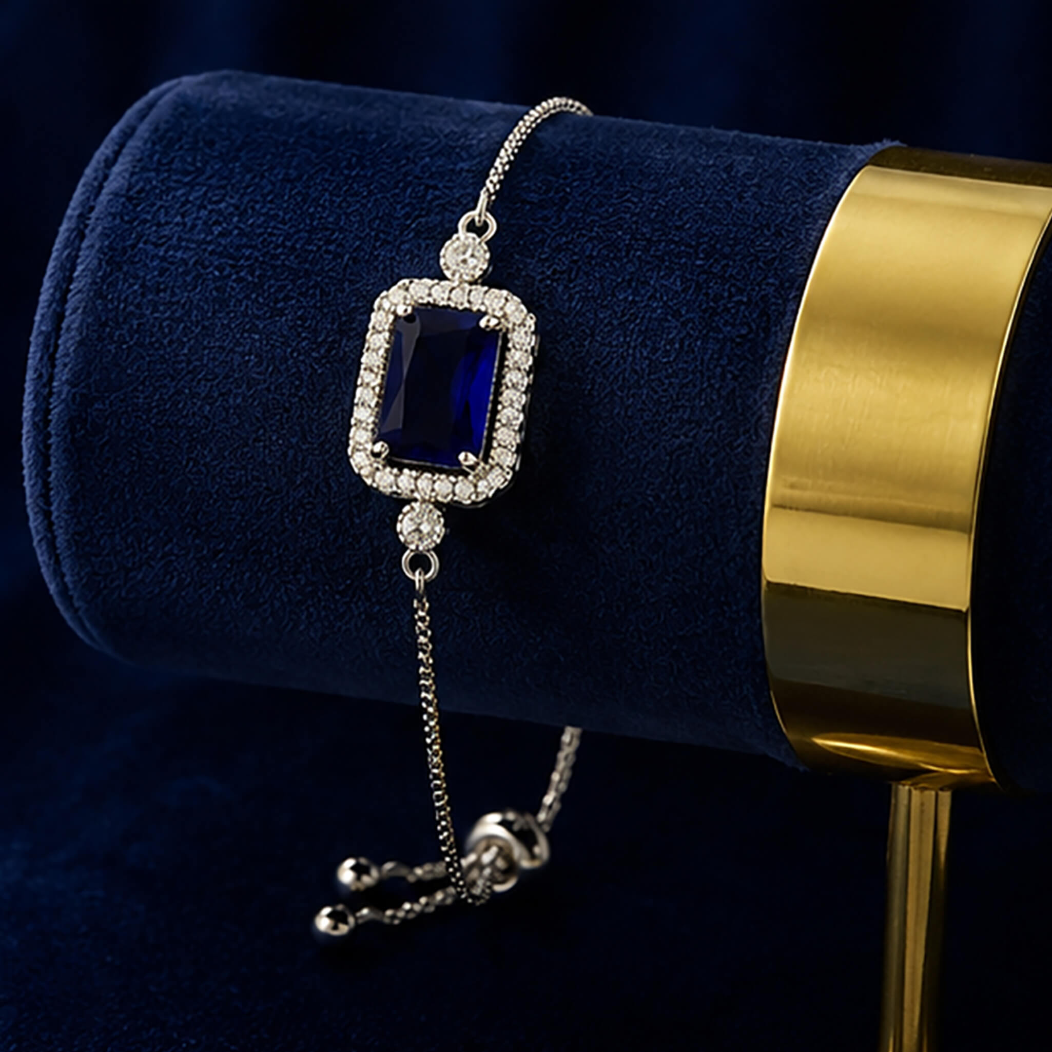 Royal blue sapphire-inspired jewelry set featuring matching earrings, pendant, bracelet, and ring on a dark blue velvet background.