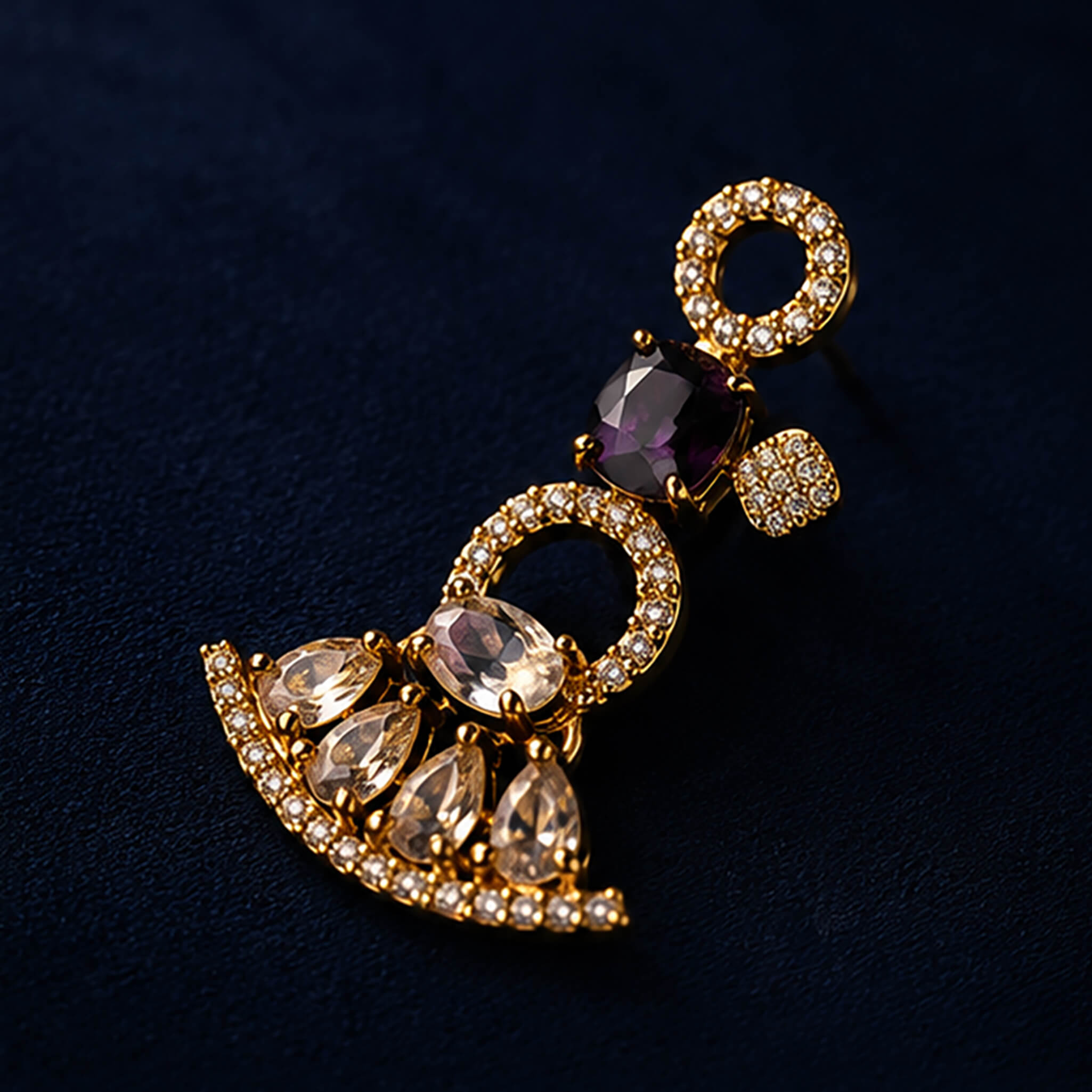 Gold-tone necklace and matching earrings set with amethyst-purple stones displayed on a luxury dark blue jewelry stand.