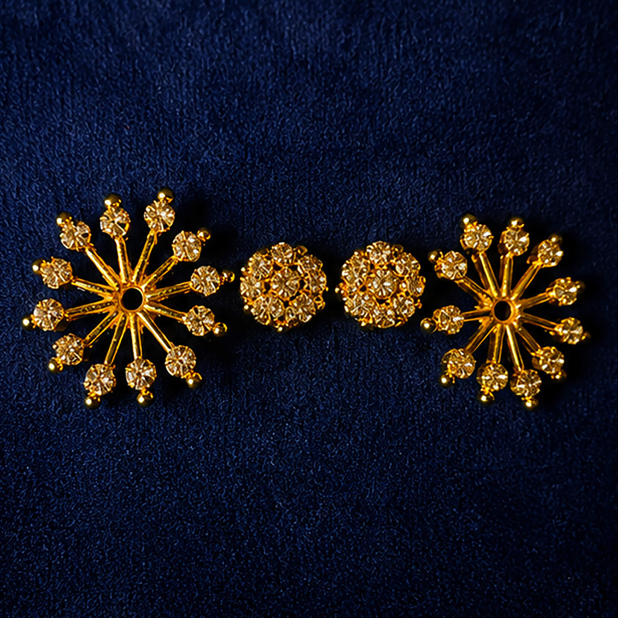 Gold-tone snowflake crystal stud earrings with sparkling stones displayed on a luxury dark blue background.