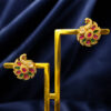 Gold-tone floral ear tops featuring pink ruby stones, green emerald stones, and sparkling crystal accents on a royal blue background.