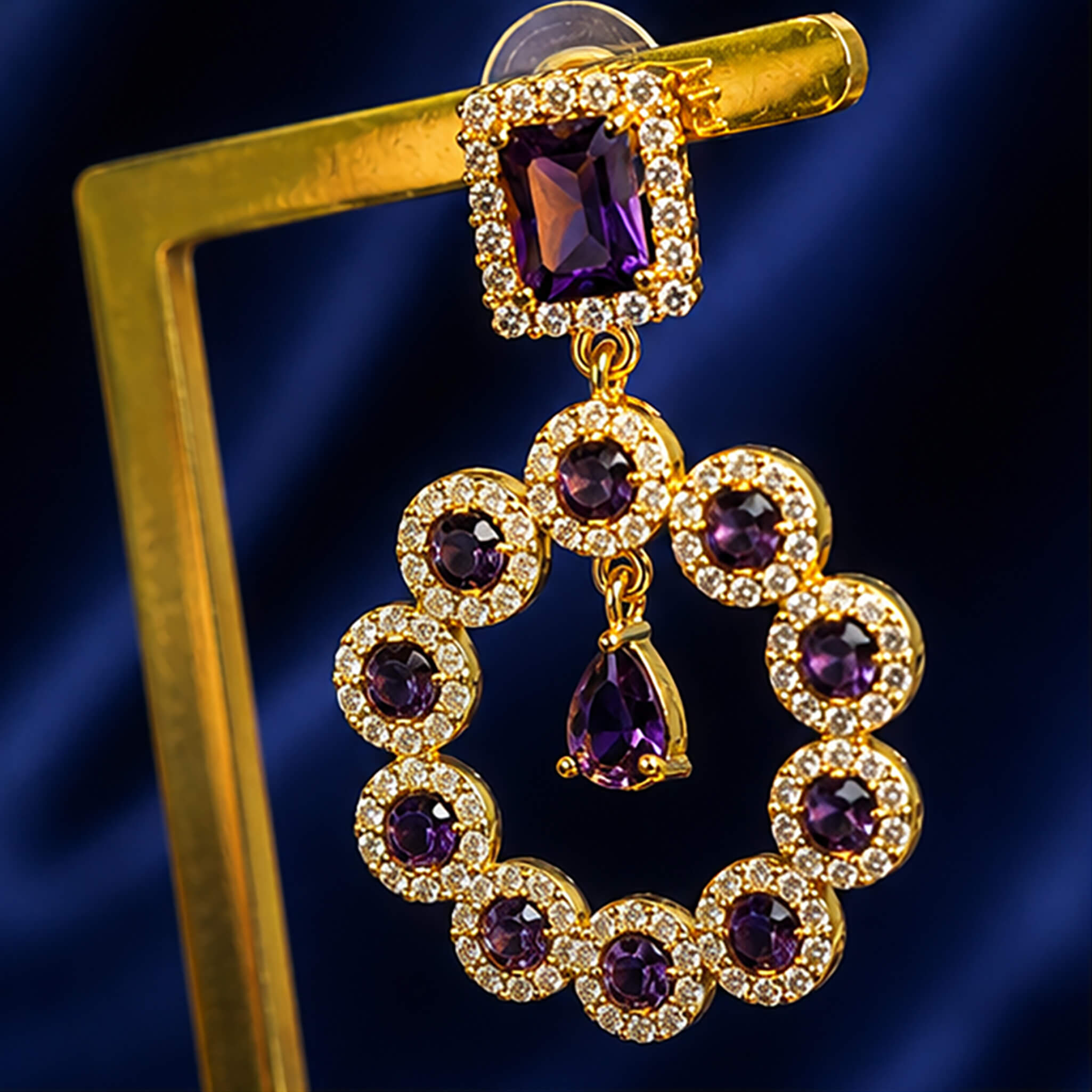 Gold-tone ear tops featuring amethyst-purple stones surrounded by sparkling crystal halos in an elegant circular design.