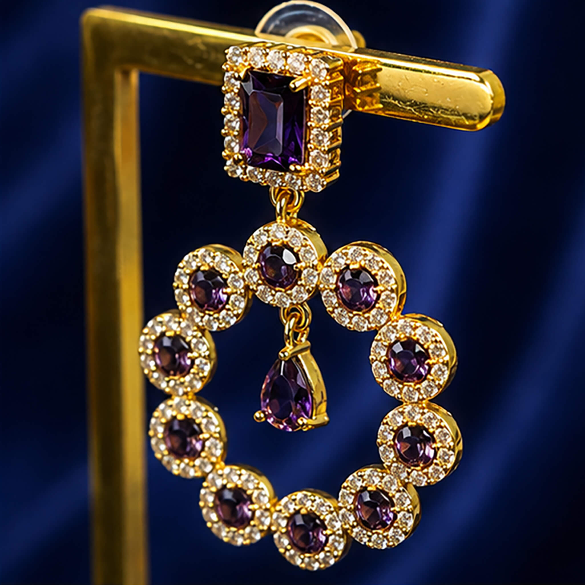 Gold-tone ear tops featuring amethyst-purple stones surrounded by sparkling crystal halos in an elegant circular design.